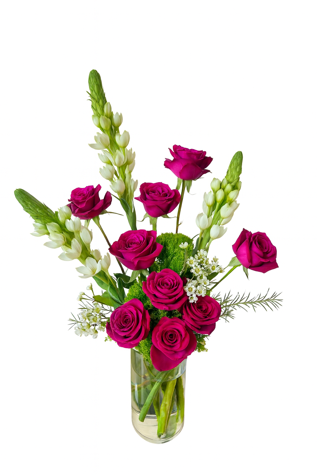 This luxurious and bold floral arrangement features a tall cylindrical glass vase filled with hot pink roses, white bouvardia, and lush green moss. The hot pink roses create a striking vertical line, complemented by elongated white bouvardia stems on either side. Accents of white wax flowers and soft greenery complete the elegant look, making this a perfect choice for a show-stopping, tall centerpiece or a dramatic romantic gesture.
