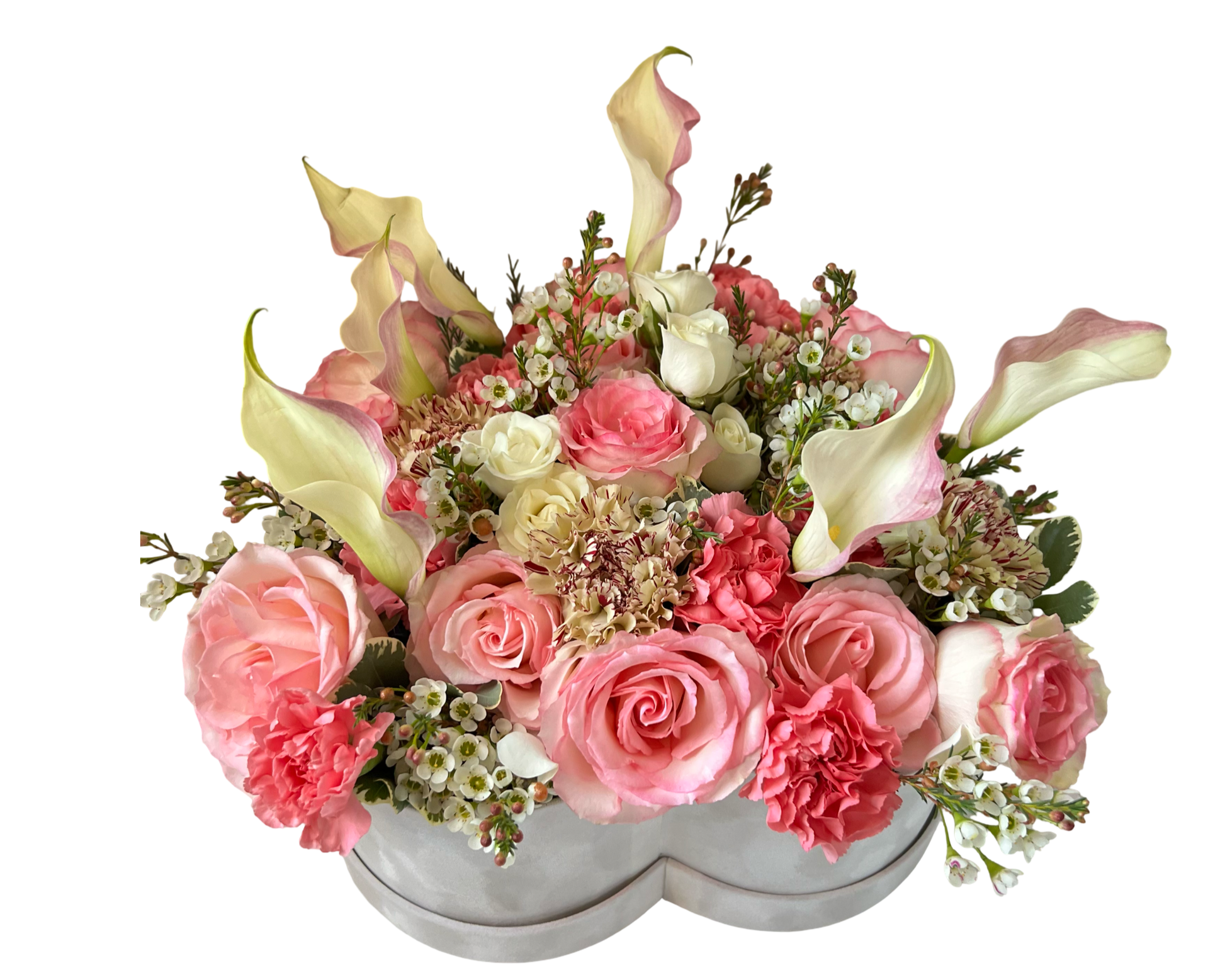 A delicate floral arrangement presented in a white heart-shaped hatbox, featuring elegant ivory calla lilies, blush and coral roses, light pink carnations, cream spray roses, and white waxflowers. With its soft curves and gentle pastel palette, this design radiates love, tenderness, and timeless beauty—ideal for romantic gestures, anniversaries, and thoughtful gifts.