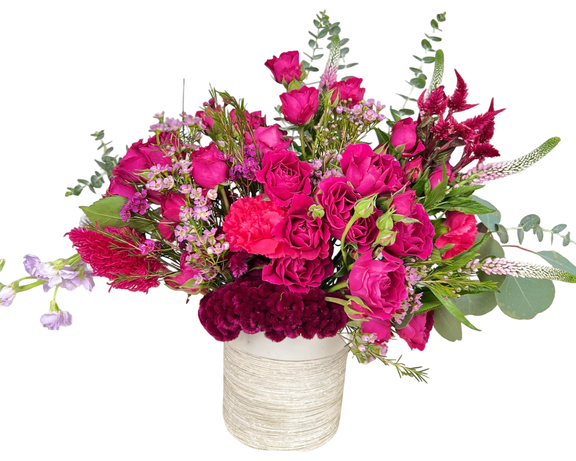 A dramatic and passionate floral arrangement set in a white textured ceramic vase, bursting with vibrant shades of deep pink, burgundy, and fuchsia. The bouquet includes hot pink spray roses, burgundy coxcomb, fuchsia carnations, pink waxflower, celosia, veronica, eucalyptus, and delicate filler blooms. Designed with height, texture, and intensity, this arrangement makes a bold romantic or celebratory statement.
