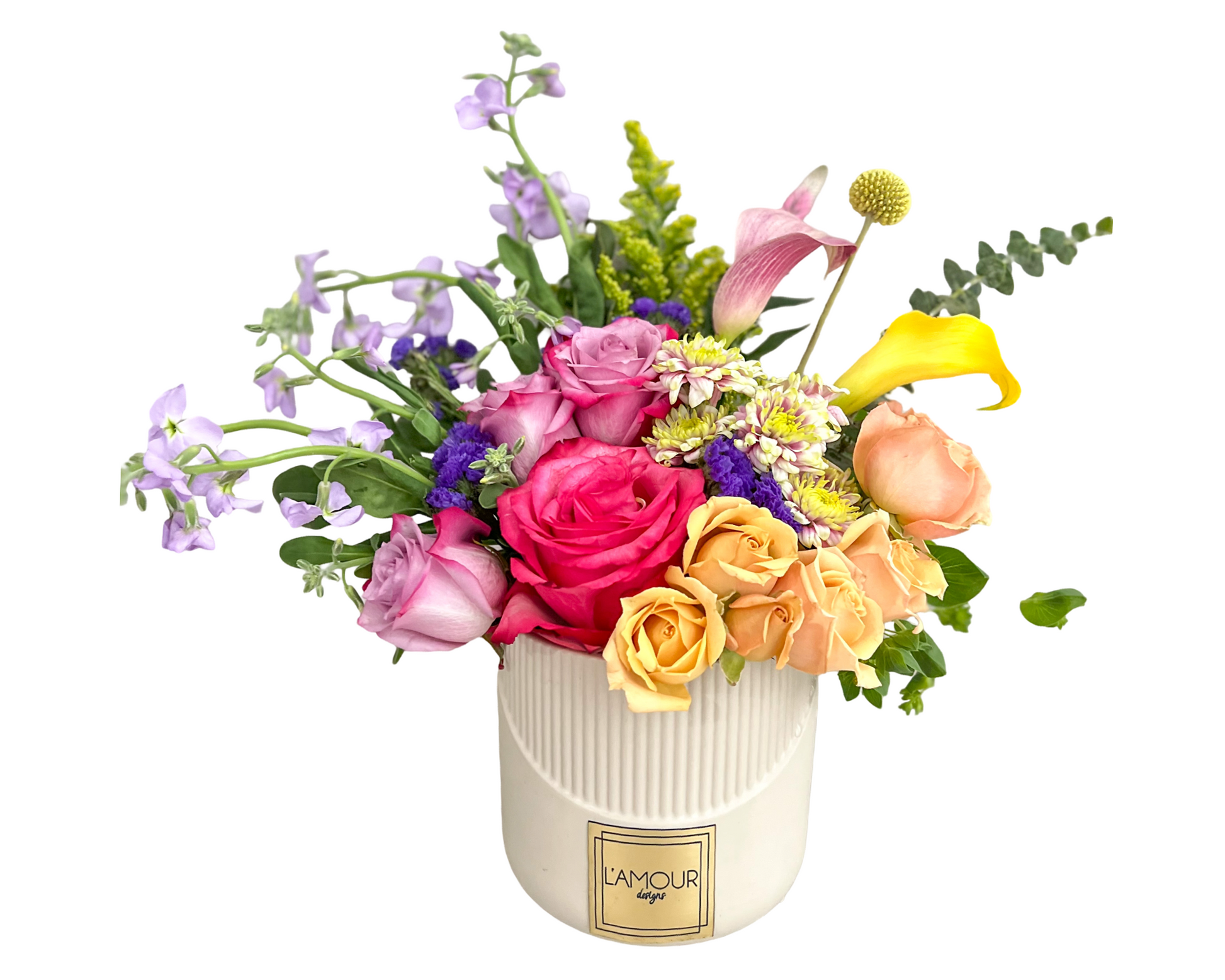 A joyful mixed floral arrangement in a ribbed ivory ceramic vase from L’amour Designs, featuring a lively palette of yellow, pink, purple, lavender, and peach tones. The bouquet includes hot pink roses, lavender roses, peach roses, yellow mini roses, yellow calla lilies, pink calla lily, purple statice, solidago, craspedia (billy ball), variegated mums, and lavender stock, arranged with a modern garden flair.