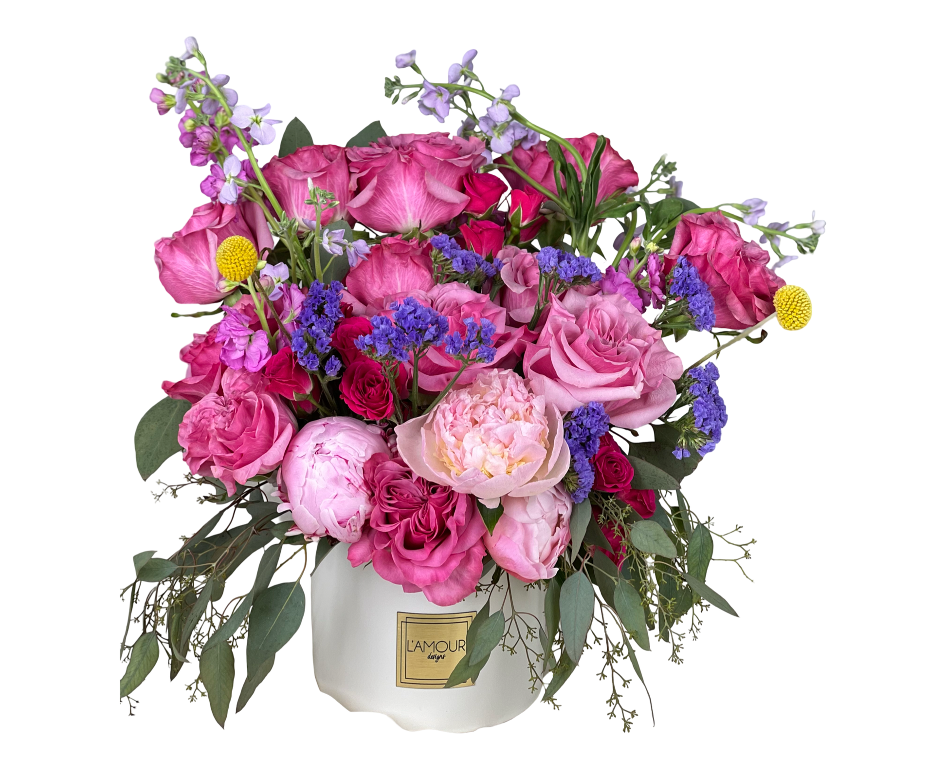 A luxurious and romantic floral arrangement in a white ceramic L'amour Designs container, featuring vibrant shades of pink, blush, lavender, and purple. The bouquet showcases pink roses, lavender roses, blush peonies, deep pink garden roses, purple statice, yellow craspedia (billy balls), and sprigs of eucalyptus and filler greenery. This energetic and elegant mix is perfect for heartfelt celebrations, romantic gestures, or feminine gifts.