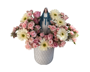 A soft and elegant floral arrangement showcasing blush pink roses, petite spray roses, cheerful white gerbera daisies, and delicate wax flowers, beautifully arranged in a textured white vase. At the center stands a serene Virgin Mary figurine, adding a symbolic and spiritual essence to the design. The gentle pastel tones make this arrangement ideal for religious celebrations such as baptisms and communions, as well as Easter, Mother’s Day, or as a heartfelt gift to express love and blessings.