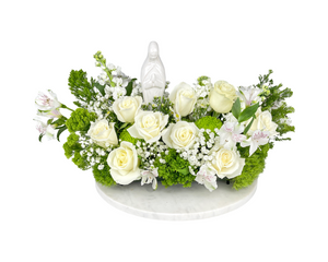 A peaceful and spiritual floral arrangement featuring pure white roses, delicate alstroemeria, baby’s breath, and soft white stock flowers, accented with lush green chrysanthemums and greenery. At the center, a serene Virgin Mary statue adds a meaningful religious touch. Arranged in a circular glass vase, this elegant display is perfect for baptisms, communions, Easter, or as a heartfelt religious gift that conveys purity, devotion, and blessings.