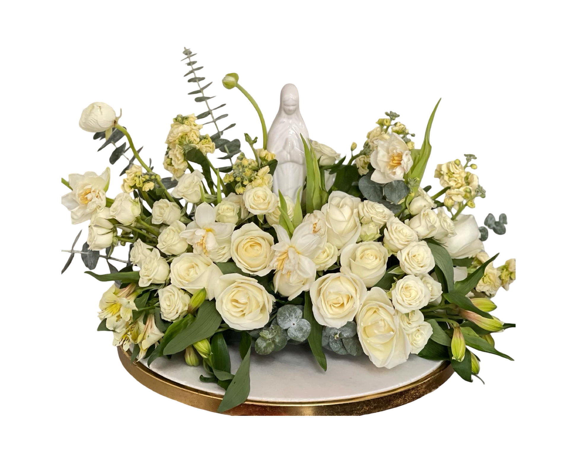 A serene and sacred white floral arrangement featuring a porcelain statue of the Virgin Mary, surrounded by ivory roses, white orchids, white lisianthus, pale yellow stock, alstroemeria, and eucalyptus, all arranged on a round white and gold base. This peaceful design is ideal for religious ceremonies, memorials, or spiritual celebrations such as baptisms and communions.