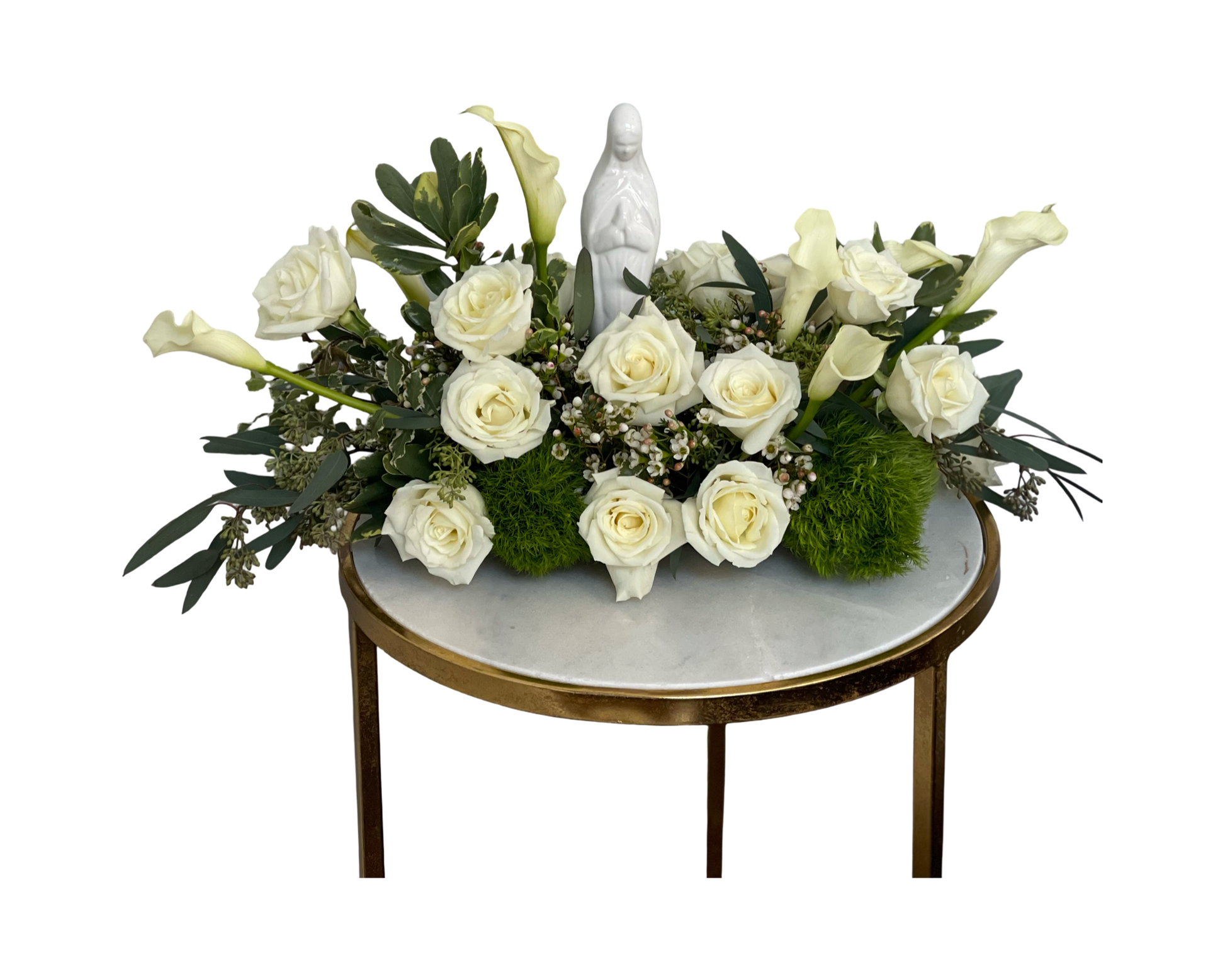 A sacred floral arrangement featuring a porcelain Virgin Mary statue at the center, surrounded by ivory roses, white calla lilies, moss, eucalyptus, waxflower, and assorted greenery. Displayed on a round marble-top table with a gold edge, this serene design is ideal for memorials, religious ceremonies, or spiritual gifts.