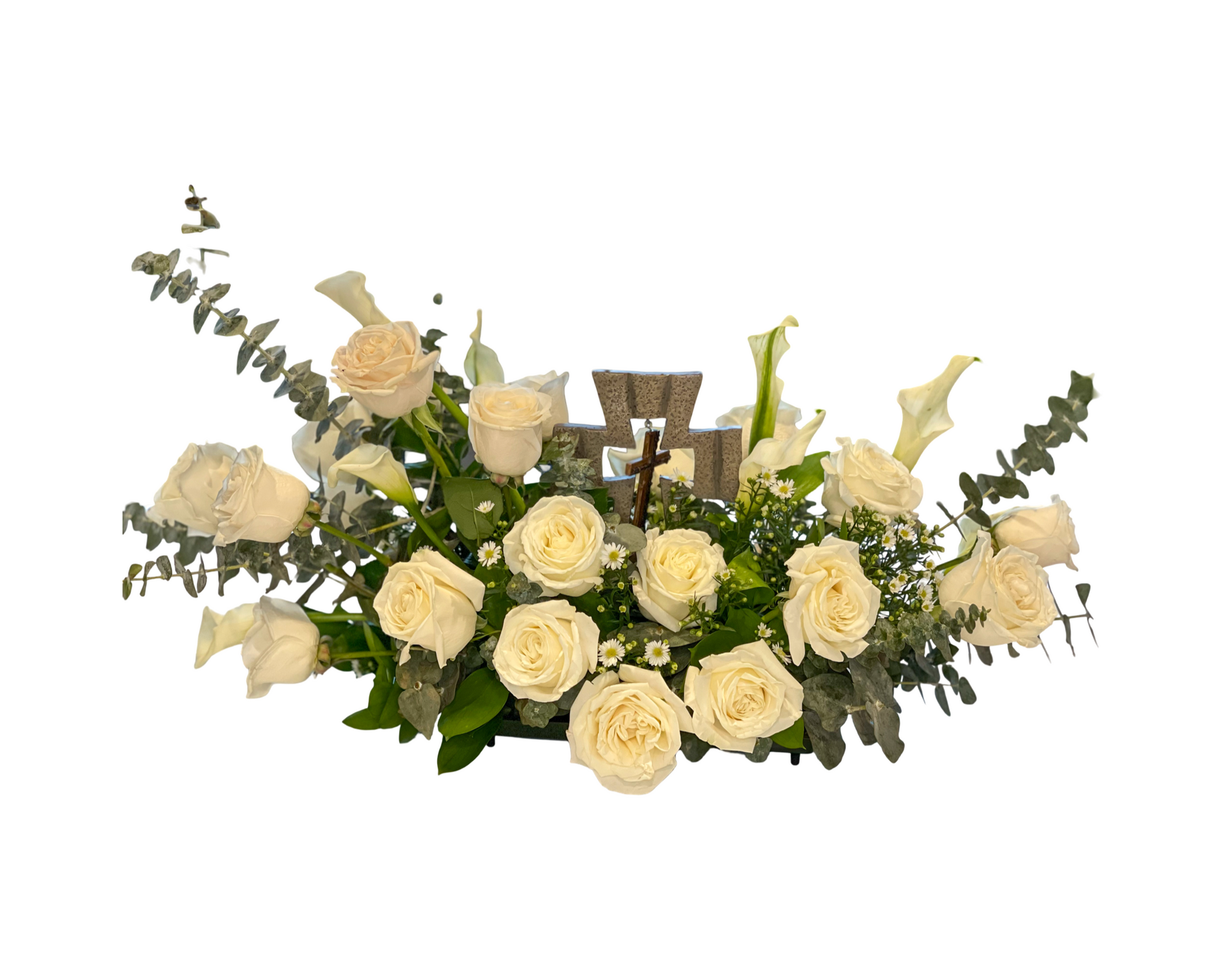 A serene sympathy floral arrangement featuring ivory roses, white calla lilies, baby’s breath, and eucalyptus, centered around a decorative stone cross with a small crucifix. This religious tribute is arranged in a low, lush format ideal for memorials, altars, or spiritual ceremonies, offering a peaceful expression of faith and remembrance.