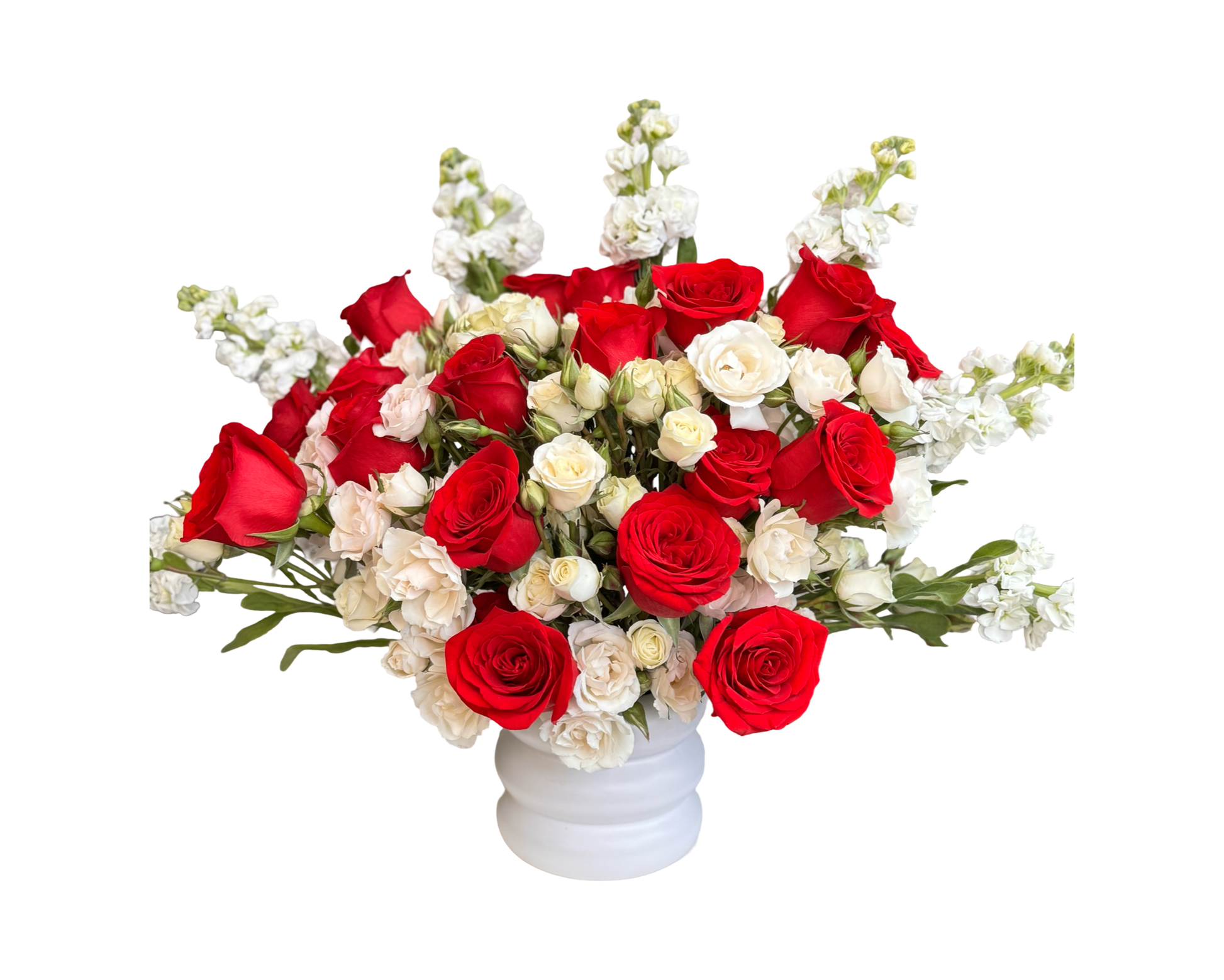 A formal and romantic floral arrangement in a white pedestal vase, featuring classic red roses, ivory spray roses, and white stock. The bold contrast of red and white blooms gives this bouquet timeless beauty, perfect for anniversaries, memorial tributes, or romantic occasions.