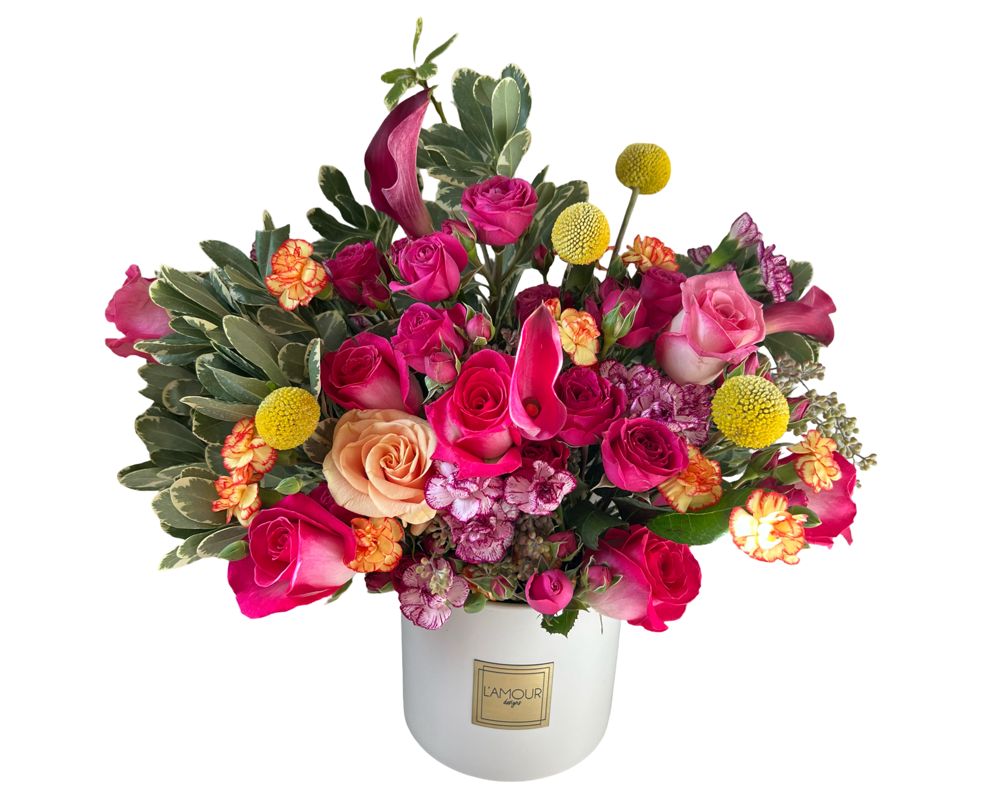 A vibrant floral arrangement in a white L’amour Designs vase featuring a lively mix of hot pink roses, peach roses, burgundy calla lilies, yellow craspedia (billy balls), orange and red carnations, two-tone variegated carnations, and lush greenery. The bold color contrast and compact design make it ideal for birthday gifting, cheerful celebrations, or brightening up any occasion.