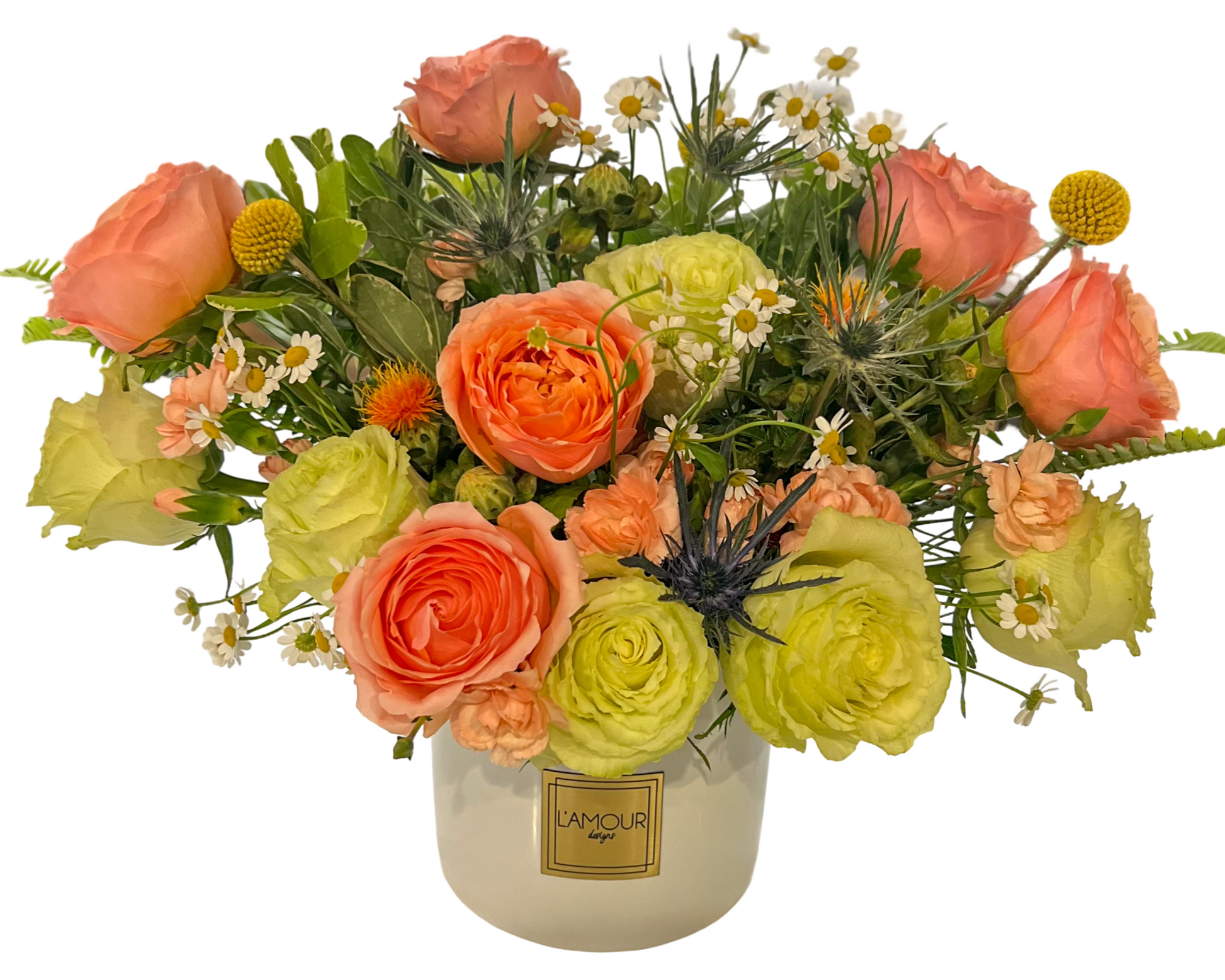 A bright and playful floral arrangement in a white ceramic vase by L’amour Designs, showcasing a cheerful mix of peach roses, lime green ranunculus, craspedia (billy balls), chamomile daisies, light orange spray carnations, blue eryngium (thistle), and safflower blooms. The organic shape and colorful palette make it ideal for uplifting moments and casual gifting.