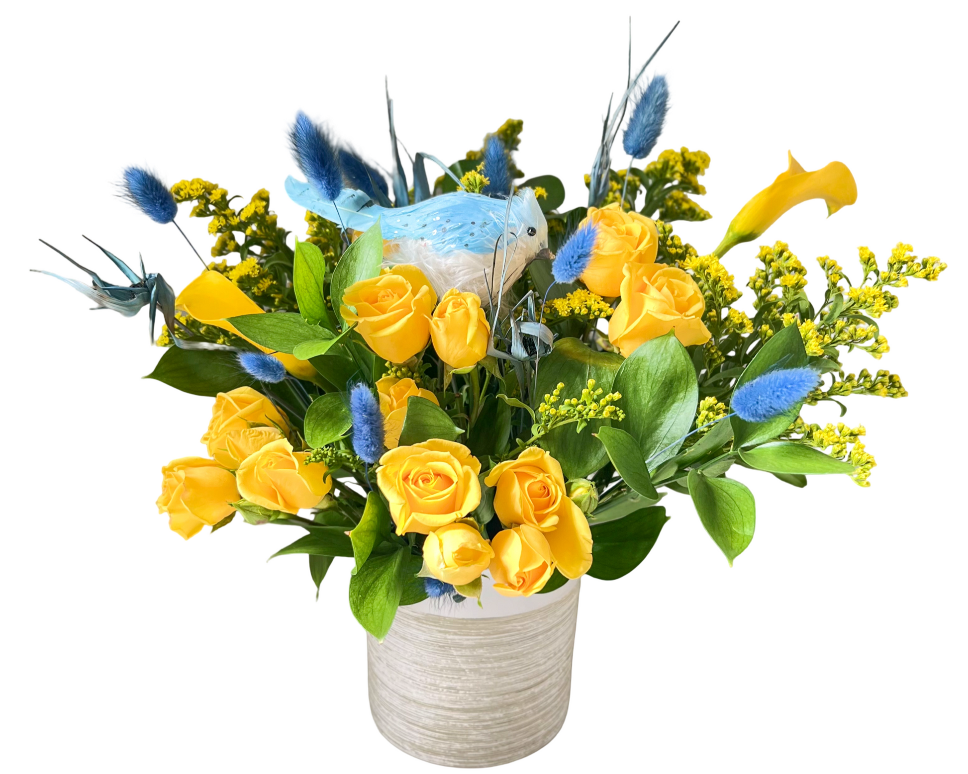 A bright and playful floral arrangement in a white textured ceramic vase featuring vivid yellow roses, yellow calla lilies, golden solidago (yellow filler), and blue dried bunny tails. Accented with a decorative artificial blue bird nestled among the flowers, this design bursts with contrasting sunny and sky tones—perfect for joyful celebrations, spring gifting, or gender reveals.
